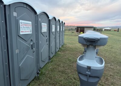 A handwashing station rental in front of a row of standard porta potty rentals.