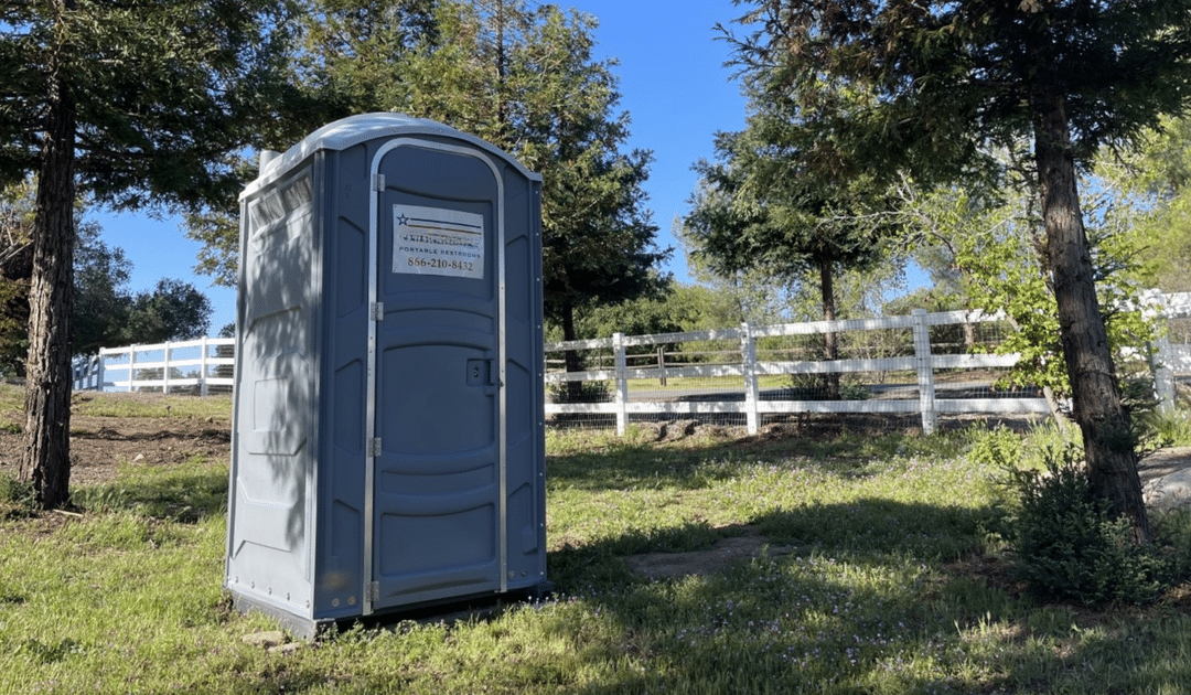 Portable restroom rental unit placed on a job site area for construction worker use.
