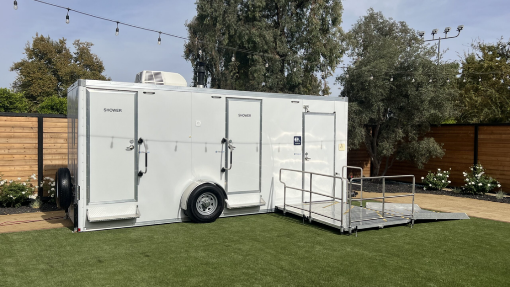 Mobile restroom trailer with showers and ADA ramp used for outdoor event sanitation planning.