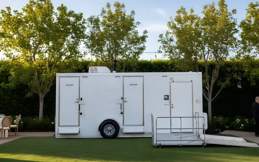 Luxury restroom trailer set up on grass for an outdoor wedding, offering upscale bathroom amenities for guests.