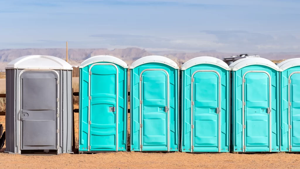 Portable toilet rental units arranged in a row at an outdoor event site, providing convenient restroom access for attendees.