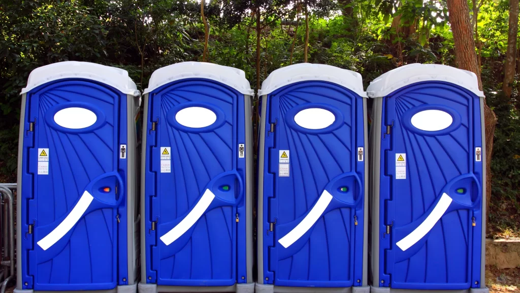 Blue portable restroom units positioned outdoors, suitable for event restroom rentals and temporary sanitation solutions.